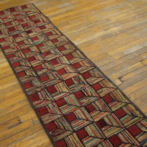 A long, textured runner rug in red and multi-colored striped squares lies on worn wooden planks.