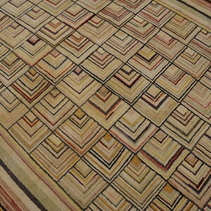 Tan, textured rug with multicolored striped chevron pattern and border on wood flooring.