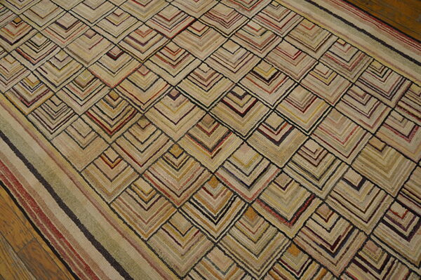 Tan, textured rug with multicolored striped chevron pattern and border on wood flooring.