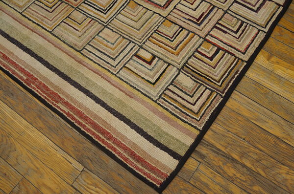 Textured, multicolored rug with angular block patterns and stripes rests on warm, wide wood plank flooring.