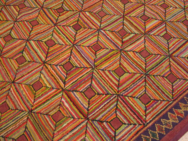 A vividly striped rug with a repeating geometric diamond pattern and a decorative dark purple border.