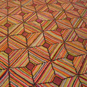 A richly textured rug displaying a colorful geometric pattern of diagonally striped diamonds.