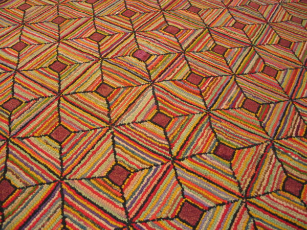 A richly textured rug displaying a colorful geometric pattern of diagonally striped diamonds.