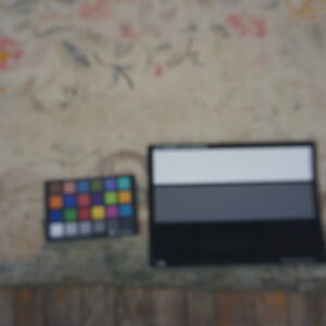 Faintly colored floral rug backdrop for a color checker and grayscale calibration card.