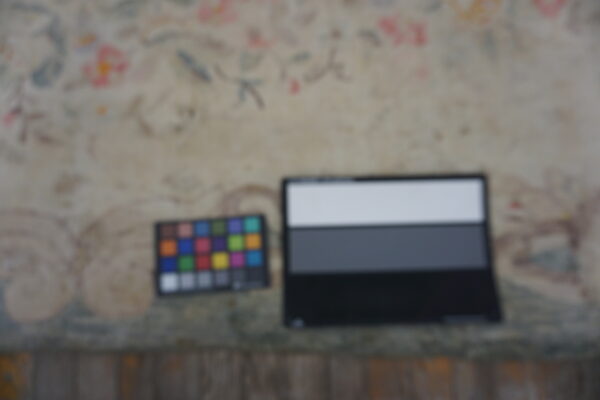 Faintly colored floral rug backdrop for a color checker and grayscale calibration card.