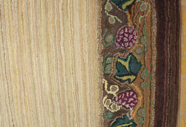 Heavily textured rug with a light striped field and a dark floral vine border in purple, green, and brown.