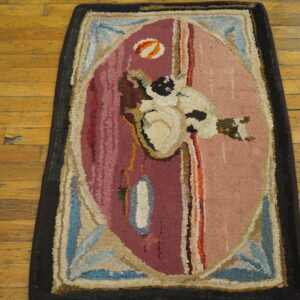 High-pile hooked rug featuring a bird motif and bold oval pattern in pinks and blues on distressed wood flooring.
