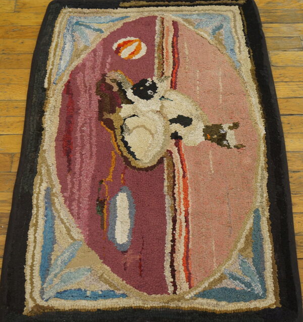 Coarse textured rug with a central abstract white figure on a split maroon and pink ground over wood flooring.