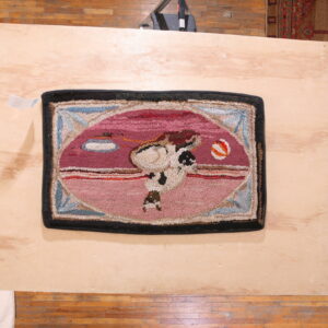 Textured pink rug featuring a magenta oval graphic of a figure is placed on a light wooden platform.