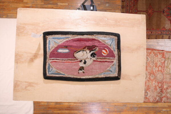 Textured pink rug featuring a magenta oval graphic of a figure is placed on a light wooden platform.