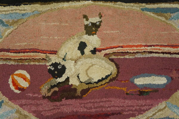 Hooked rug detail featuring two cream lambs with dark faces on a pink and purple textured field.