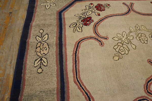Textured floral rug in beige, gray, red, and blue resting on yellow-toned plank flooring.