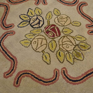 Textured beige rug with a floral pattern of red and pale roses, framed by wavy black, rust, and gold borders.