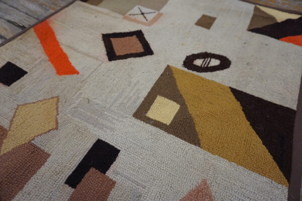 Chunky loop pile rug featuring abstract orange, mustard, and brown geometric shapes on wooden flooring.
