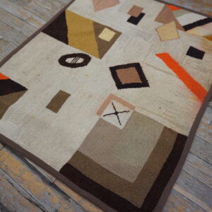 Textured loop pile rug featuring abstract brown, cream, and orange geometric shapes on distressed wood planks.