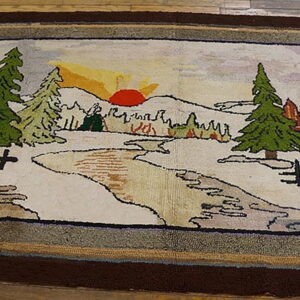 Textured rug with a scenic landscape pattern of snow, green trees, a sun, and thick brown borders on wood flooring.