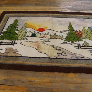 Low-pile rug depicting a rustic landscape of trees, stream, and sunset, framed by thick brown borders on wood floor.