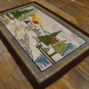 A rectangular rug featuring a detailed mountain landscape scene with green trees and a thick dark brown border.