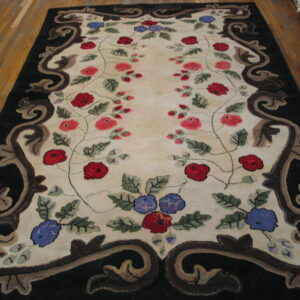 Cream rug with red and blue floral vines and a thick black, brown scroll border on hardwood.