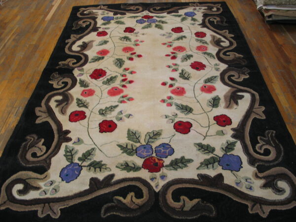 Cream rug with red and blue floral vines and a thick black, brown scroll border on hardwood.