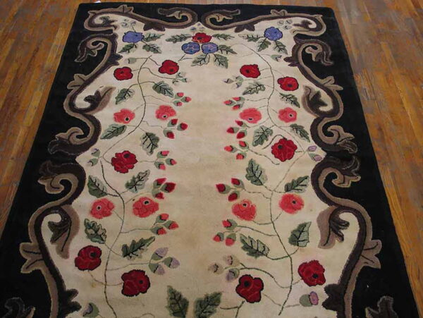 High-pile rug featuring red and blue florals on a cream ground with a black scrolled border on wood.