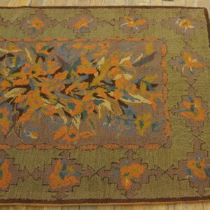 Textured brown and olive green rug with a dense orange, blue, and gold floral pattern on a wood floor.