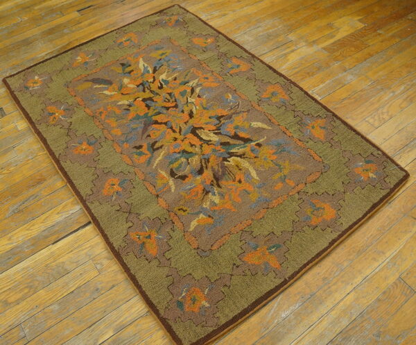 Low-pile rug in brown, olive, and orange featuring an abstract floral design on distressed wood plank flooring.