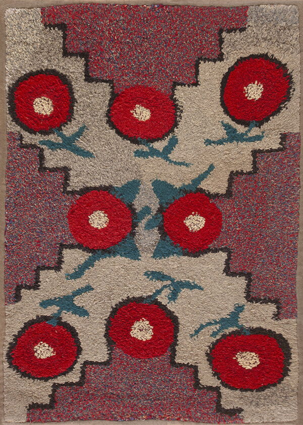 High-pile rug with red floral motifs, teal leaves, and stepped geometric borders on a heathered gray field.