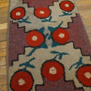 Red and gray high-pile rug with geometric floral pattern resting on distressed wood floorboards.