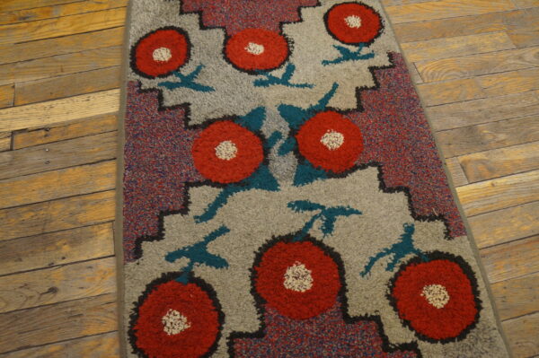Red and gray high-pile rug with geometric floral pattern resting on distressed wood floorboards.