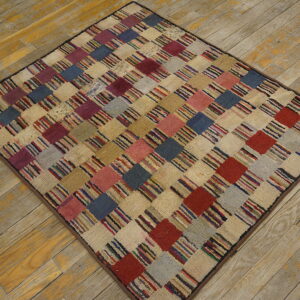 A multicolored, textured rug featuring a checkerboard pattern rests diagonally on distressed wooden floorboards.
