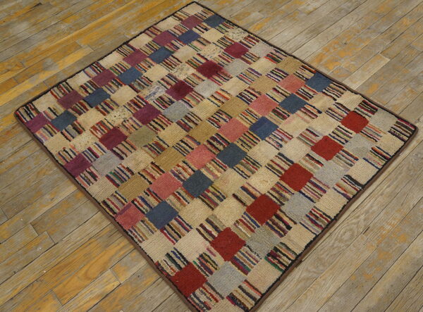 A multicolored, textured rug featuring a checkerboard pattern rests diagonally on distressed wooden floorboards.