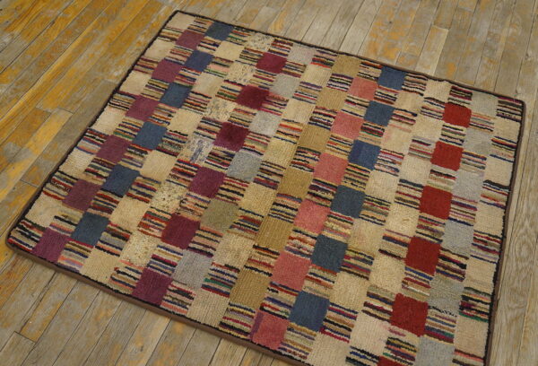 Patchwork rug with multicolored striped and solid squares resting on distressed light wood flooring.