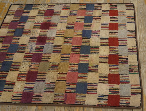 Textured rug with a striped, multicolored checkerboard pattern resting on light wooden floorboards.