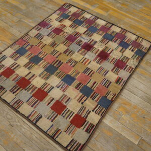 A multicolored checkerboard rug with textured squares sits on distressed yellow and gray wood flooring.