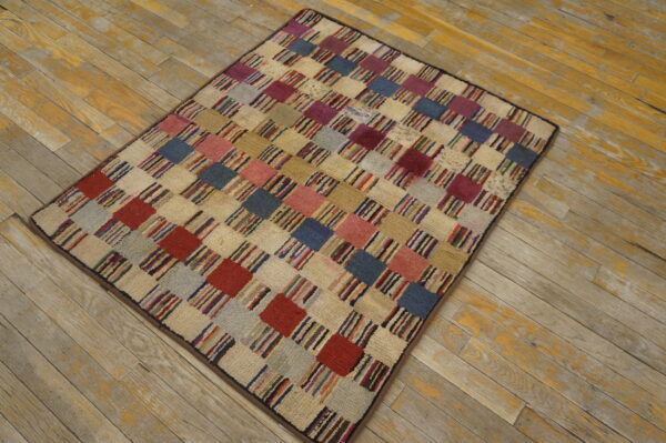 A multicolored checkerboard rug with textured squares sits on distressed yellow and gray wood flooring.