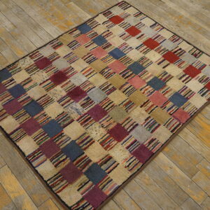 Checkerboard rug featuring textured squares in multicolored stripes, cream, blue, and red on distressed wood flooring.