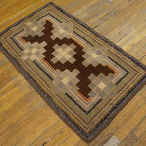 Low-pile rug with geometric brown and tan stepped designs and concentric borders on light wood floor.