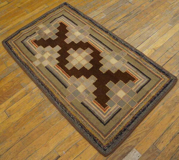 Low-pile rug with geometric brown and tan stepped designs and concentric borders on light wood floor.