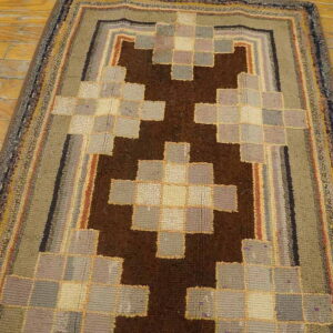 A chunky pile runner rug with a stepped brown and multicolored checkerboard design lies on wood flooring.