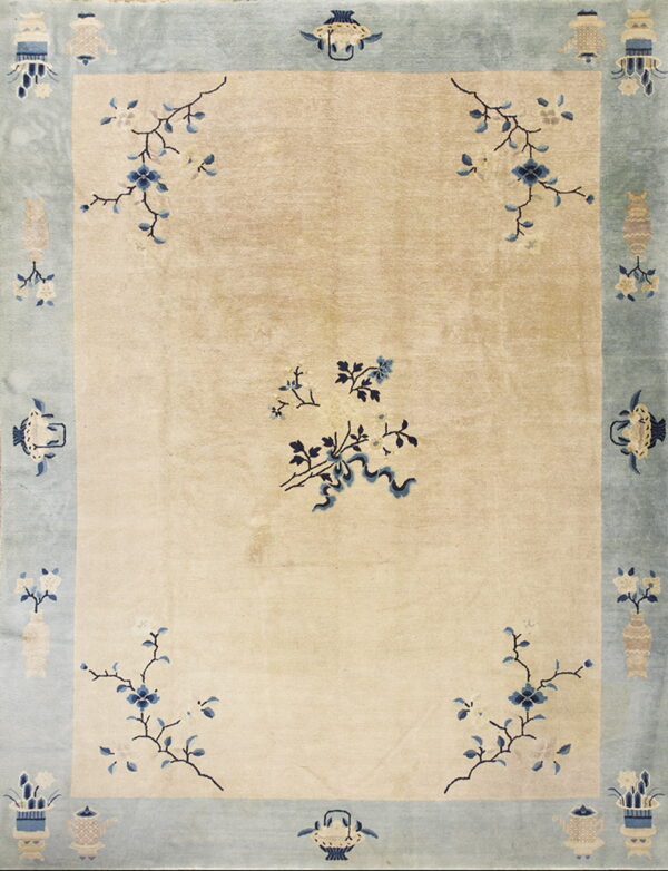 Cream rug with blue floral sprays and a wide, pale blue border patterned with beige vases and lanterns.