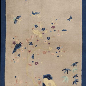 Pictorial tan rug featuring a wide blue border, blooming tree, birds, and stylized rocks.