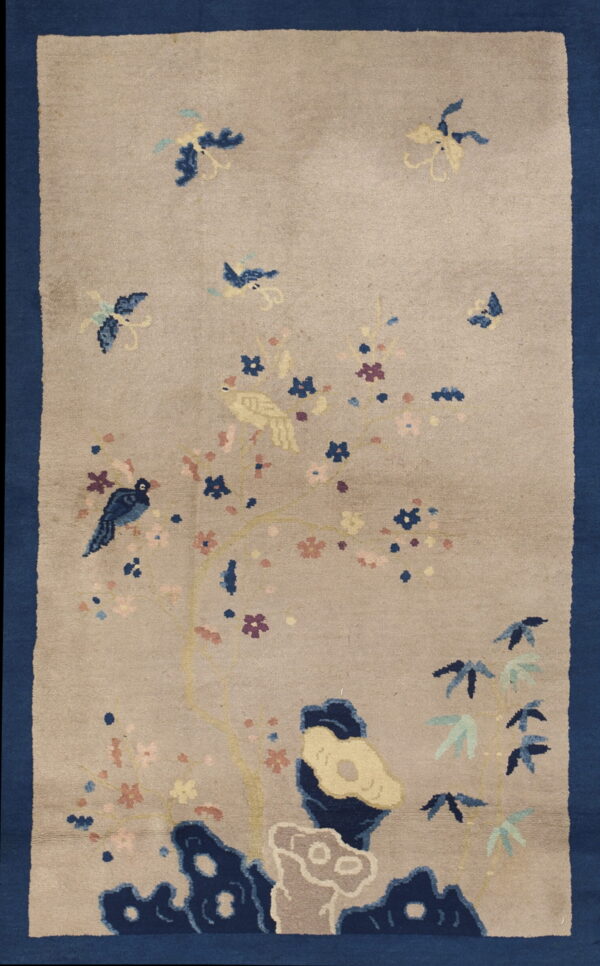 Pictorial tan rug featuring a wide blue border, blooming tree, birds, and stylized rocks.