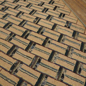 Looped tan rug with blue and teal stripes in a diagonal basketweave pattern on wood flooring.