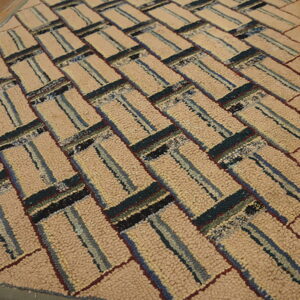 Chunky hooked rug in beige and multi-colored stripes forms a diagonal pattern on a wood floor.