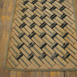 Textured beige rug with a diagonal striped block pattern in blue, green, and maroon rests on wood flooring.