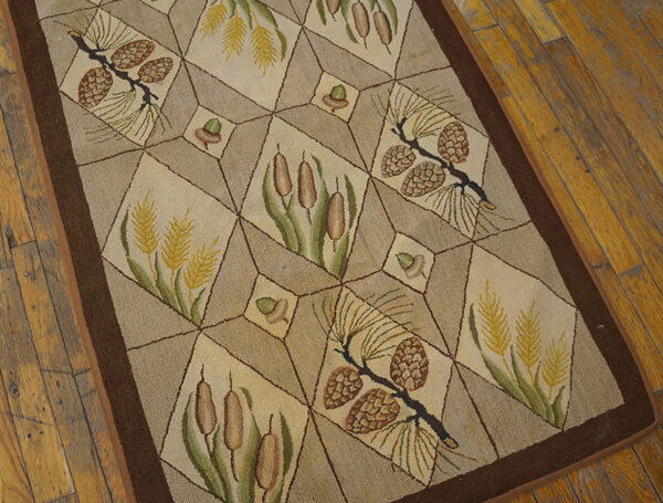 Tan rug with a geometric grid pattern showcasing pinecones, cattails, and wheat on distressed wood flooring.