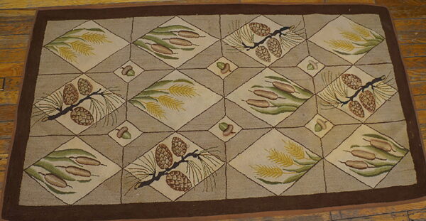 Brown and tan rug featuring a lattice design with pine cones, cattails, and wheat motifs on a wood floor.