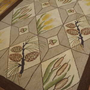 Beige and tan rug with a geometric grid pattern featuring pinecones, cattails, and wheat on a distressed wooden floor.