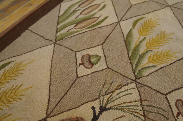 Close-up of a loop pile rug with a geometric pattern, featuring botanical motifs like acorns and cattails.